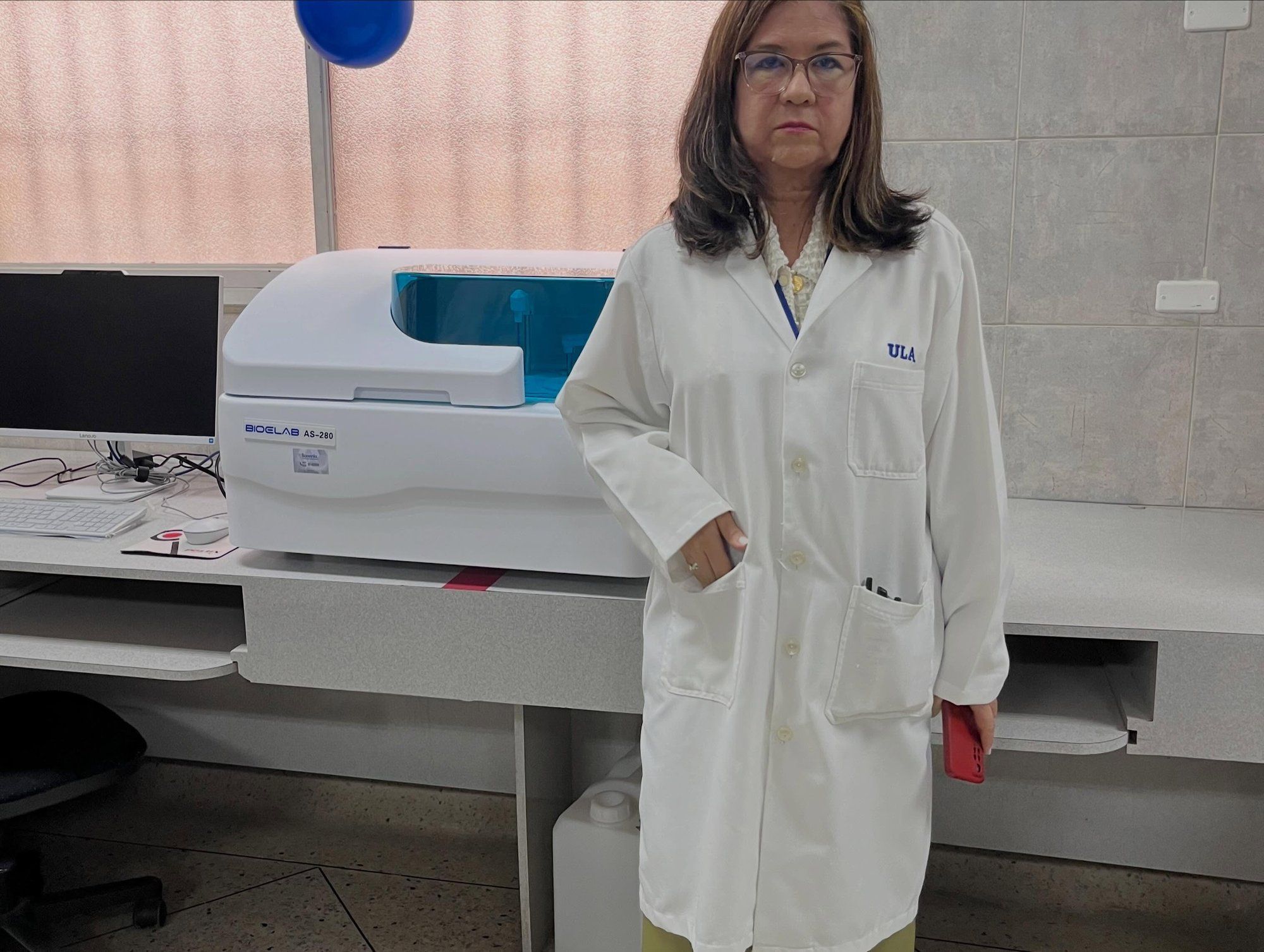 Una profesional del laboratorio, con bata blanca, junto al nuevo equipo